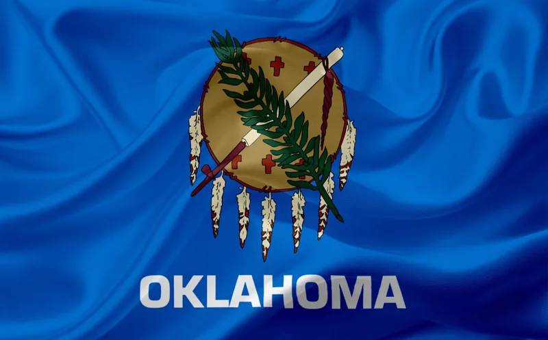 Oklahoma state flag with an Osage shield, olive branch, and peace pipe on a blue field