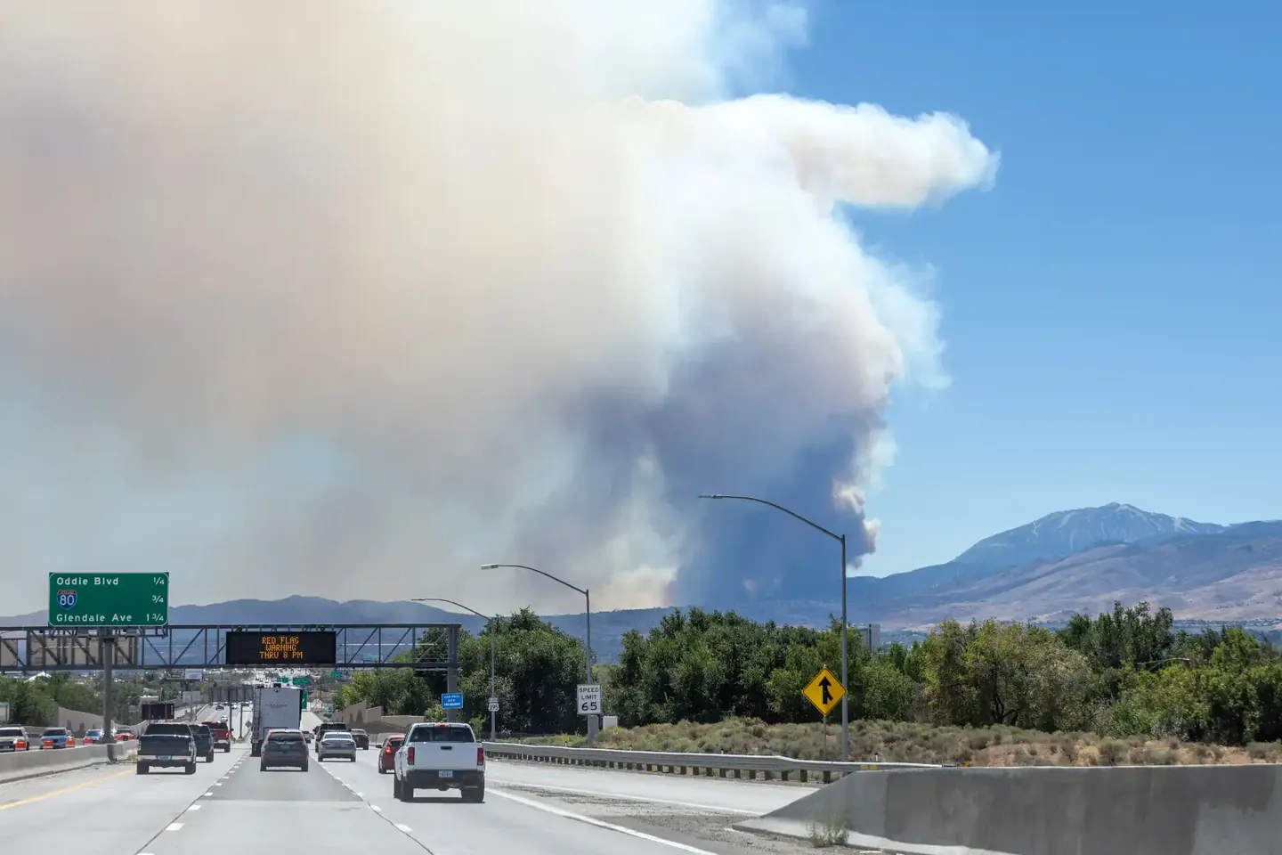Highway and streetlights beneath a large distant smoke plume