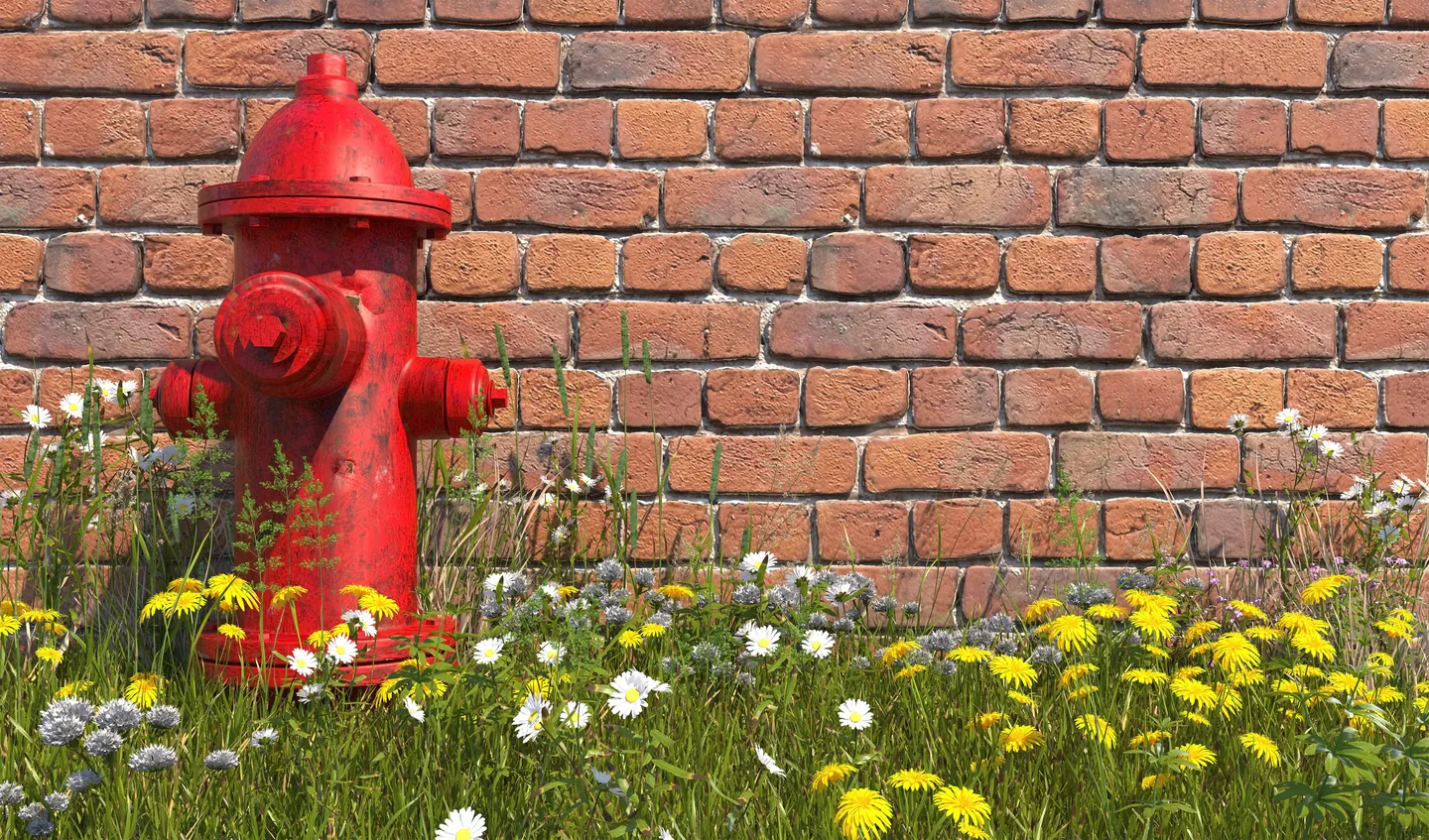 Red fire hydrant beside a brick wall and wildflowers